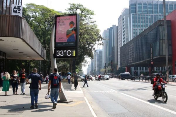 foto colorida de pedestres caminhando sob o sol na Avenida Paulista; termômetro de rua marca 33° C - Metrópoles