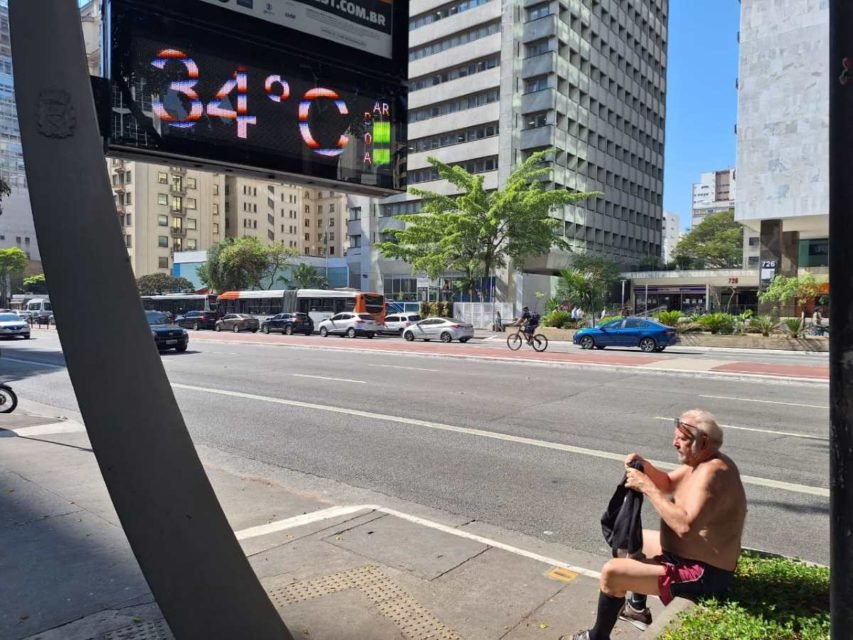 foto colorida de homem sentindo calor sem camisa na Avenida Paulista, perto de termômetro que marca 34 graus - Metrópoles