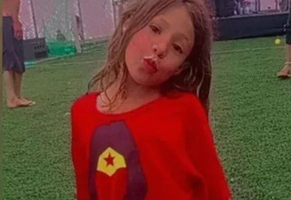 Imagem colorida mostra a menina Lana, de 8 anos, uma criança branca, de cabelos loiros, lisos, vestindo uma camiseta vermelha - Metrópoles