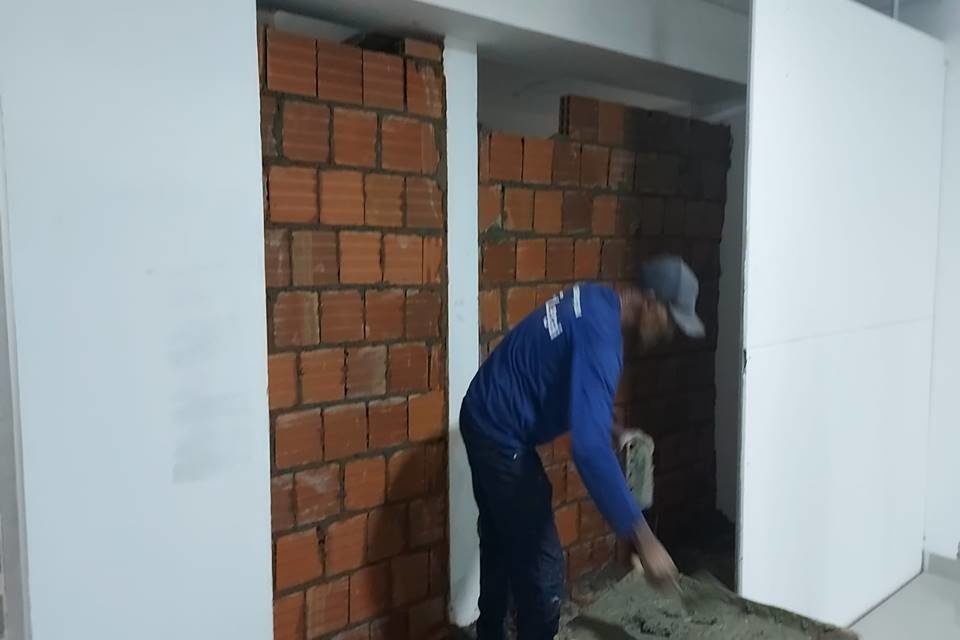homem de uniforme azul da secretaria DF Legal faz parede de tijolos em obra