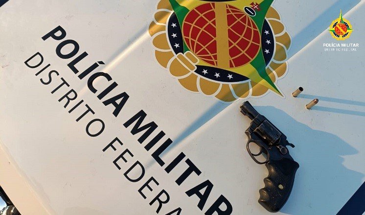 Foto colorida de uma arma de fogo em cima de uma viatura - Metrópoles