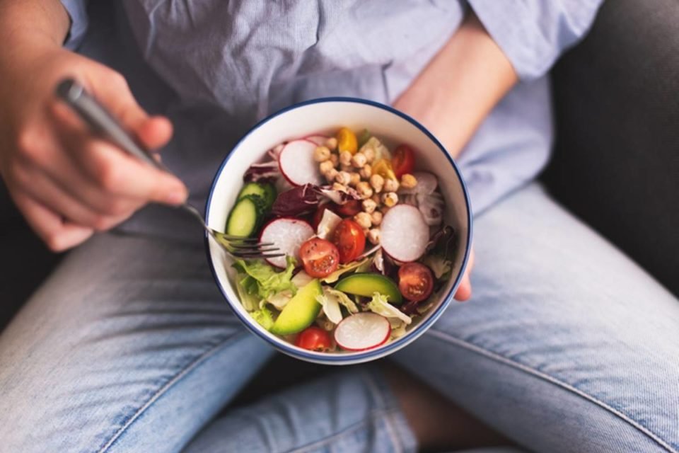 Imagem colorida de pessoa sentada de pernas cruzadas enquanto pratica uma dieta vegana - Metrópoles