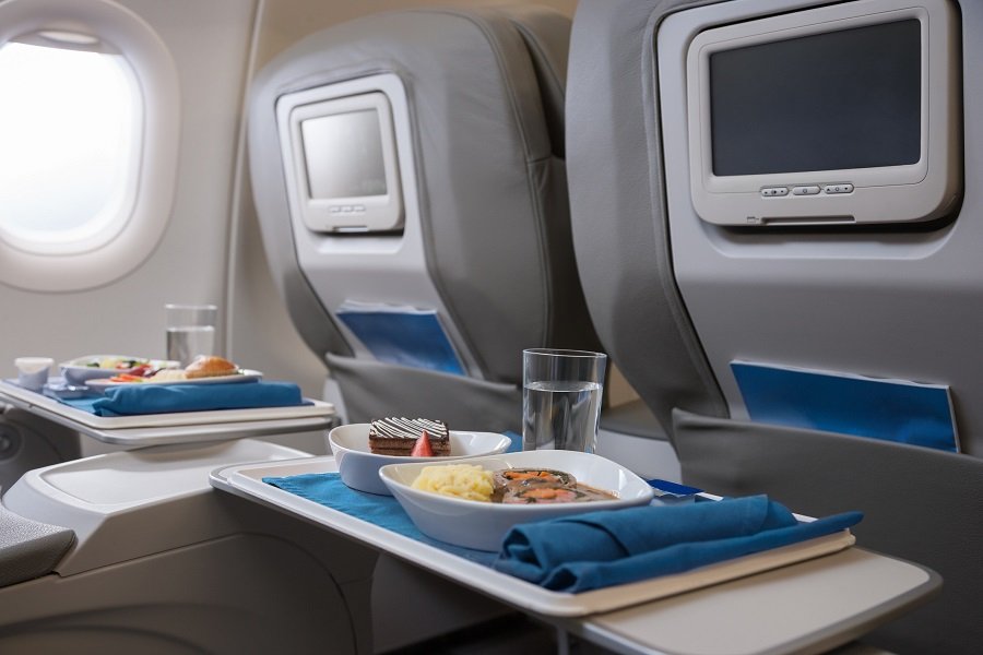 Imagem colorida mostra refeição com parte do cardápio servido em aeronave com prato principal, sobremesa e copo d'água - Metrópoles