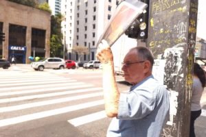 foto colorida mostra idoso se protegendo do sol com jornal em trecho da Avenida Paulista - Metrópoles