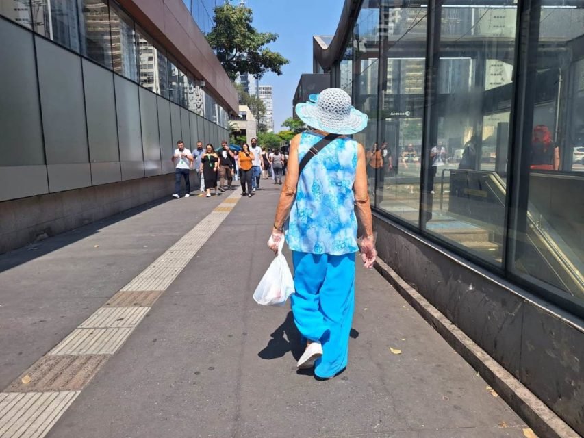 foto colorida mostra mulher caminhando de chapéu sob sol em trecho da Avenida Paulista; SP vive onda de calor atípico - Metrópoles
