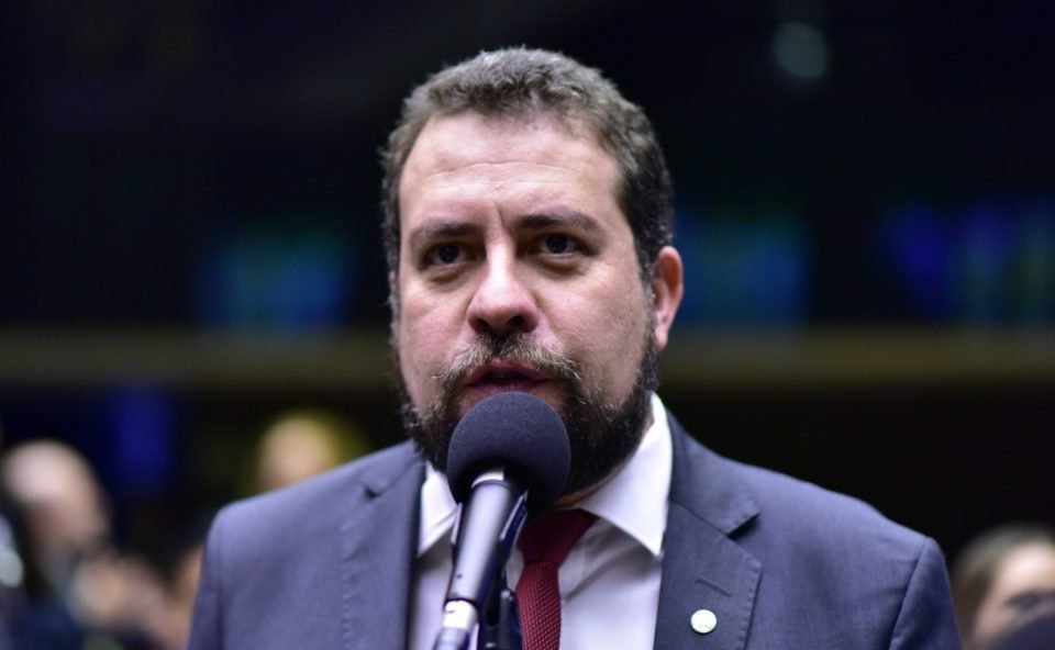 Imagem colorida mostra Guilherme Boulos, dos ombros para cima, de terno e gravata, falando ao microfone no Congresso - Metrópoles