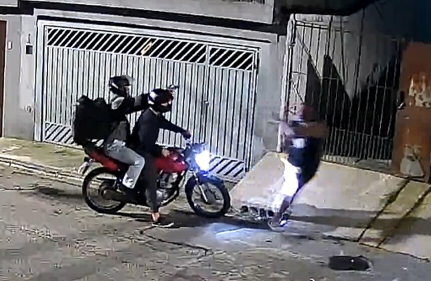 Em foto colorida garupa de moto aponta arma para homem acima do peso, que corre - Metrópoles
