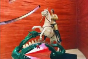 Imagem colorida de escultura de São Jorge montado em um cavalo a frente de um dragão - Metrópoles