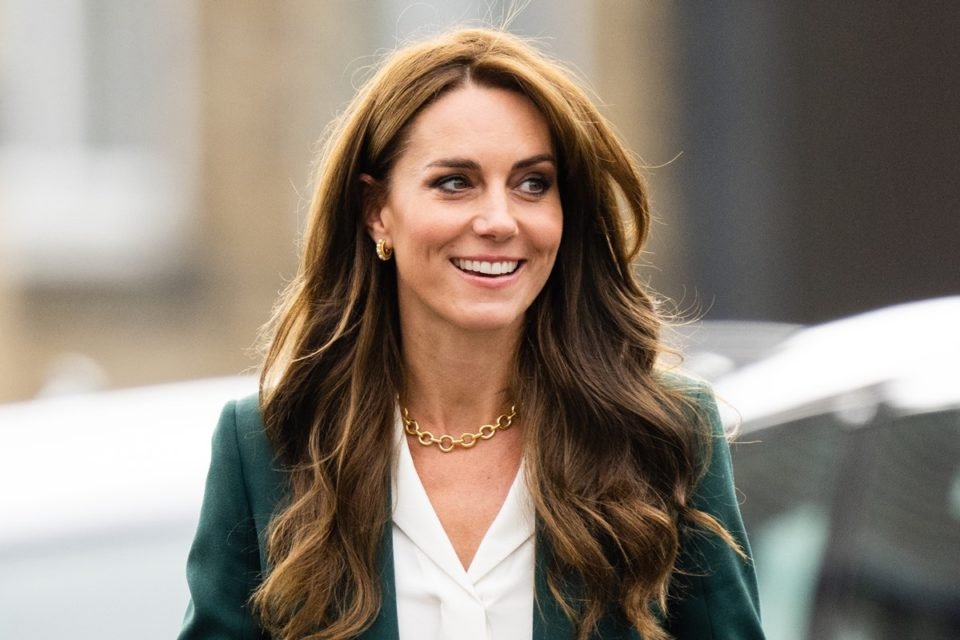 Foto colorida. Kate Middleton, uma mulher branca, de cabelos longos, castanhos claros e meio ondulados, está usando um terninho verde e sorrindo - Metrópoles