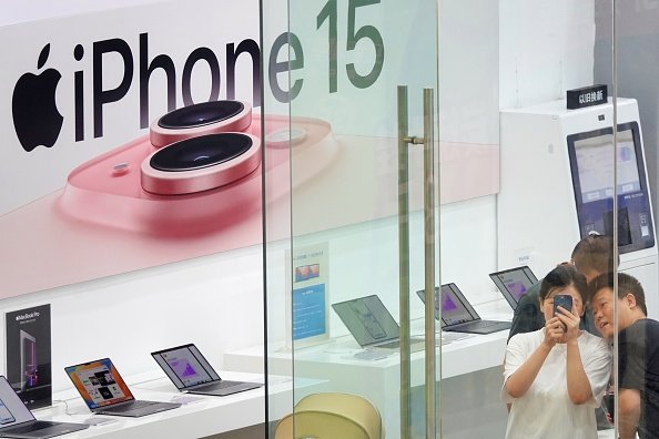 Imagem de loja de eletroeletrônicos com banner do iPhone 15, lançamento da Apple, e consumidores tirando fotos - Metrópoles