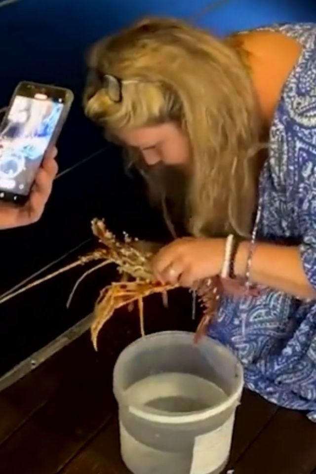 Foto colorida de uma mulher segurando uma lagosta - Metrópoles