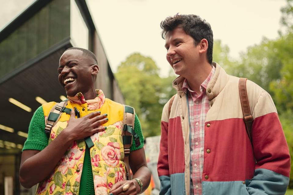 Foto colorida de dois jovens de roupas coloridas rindo juntos - Metrópoles