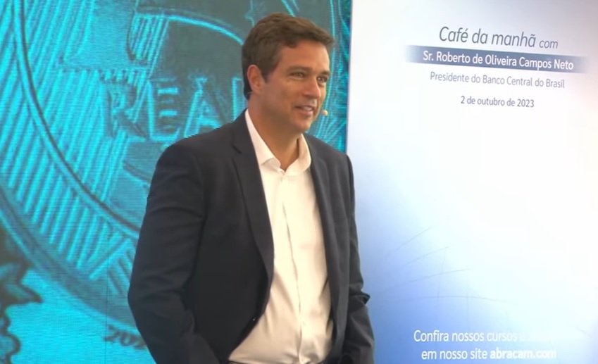 Imagem de Roberto Campos Neto, presidente do Banco Central, durante palestra. Ele veste um terno escuro, sem gravata, e camisa branca - Metrópoles