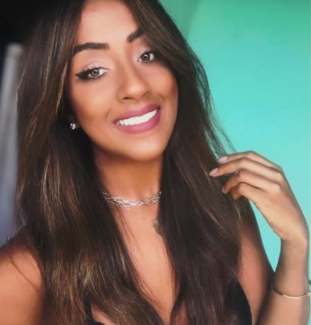 foto colorida. Mulher negra com cabelo preto liso sorrindo