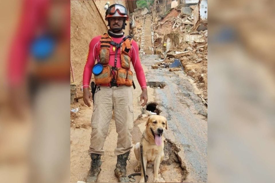 Fotografia colorida do cão de resgates Thayron ao lado de seu tutor subtenete Tavares