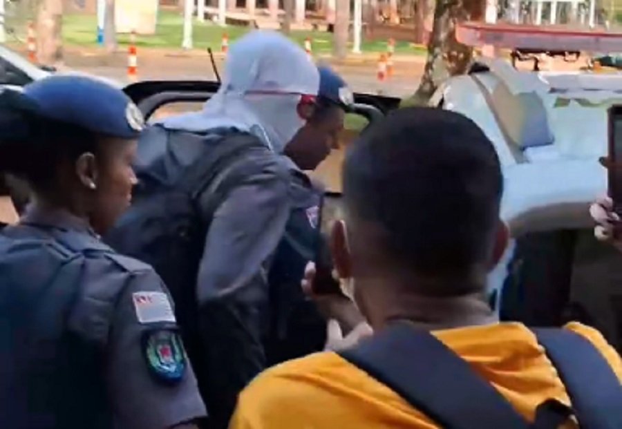 Imagem colorida mostra homem encapuzado sendo colocado em viatura da polícia - Metrópoles