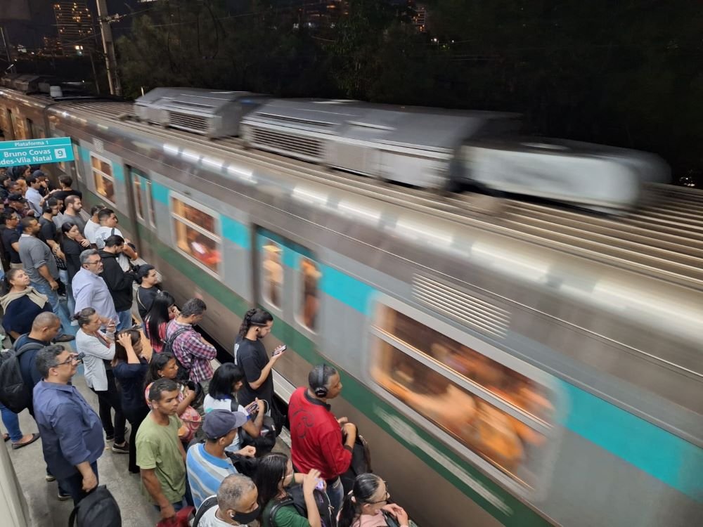 Imagem colorida mostra trem passando na linha 9 da CPTM, administrada pela ViaMobilidade, em São Paulo, enquanto pessoas esperam pelo lado de fora - Metrópoles