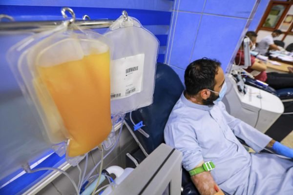 Foto colorida de homem sentado enquanto faz transfusão de plasma - Metrópoles