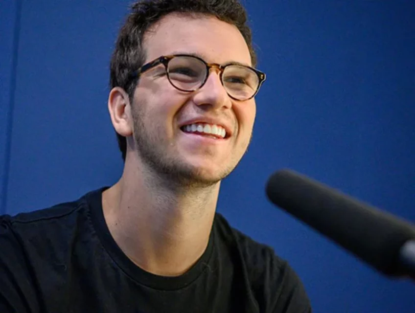 Henrique Dubugras é clicado durante um evento, sorrindo - Metrópoles