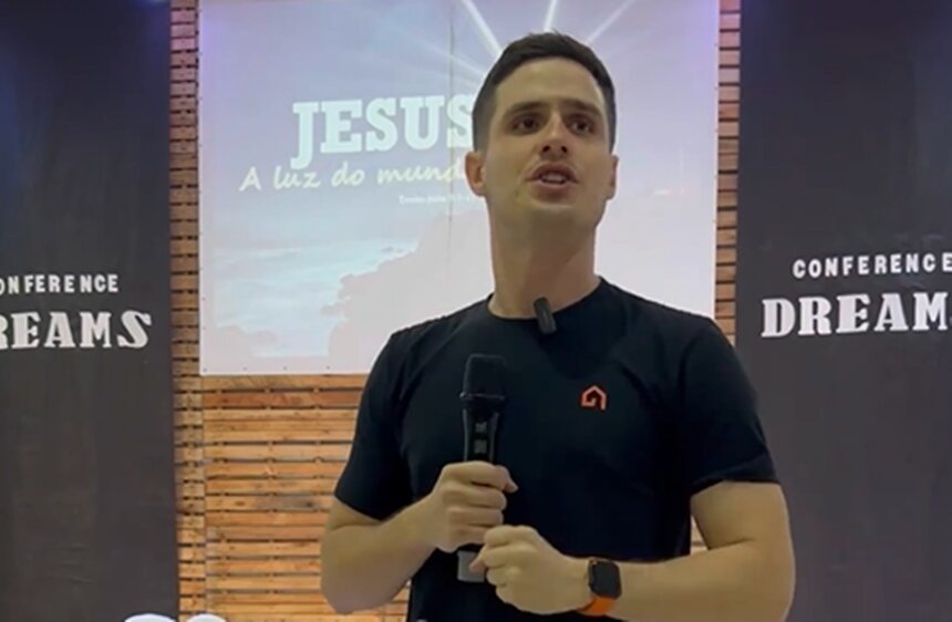 Em foto colorida homem branco segura microfone na altura do pescoço com o nome Jesus em um telão ao fundo - Metrópoles