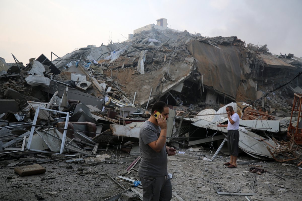 Palestinos se reúnem próximo às ruínas da Torre Watan, que foi destruída em ataques israelenses, na cidade de Gaza, em 8 de outubro de 2023
