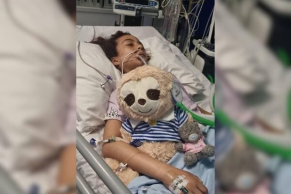 Imagem colorida de menina entubada no hospital abraçada em bicinho de pelucia - Metrópoles