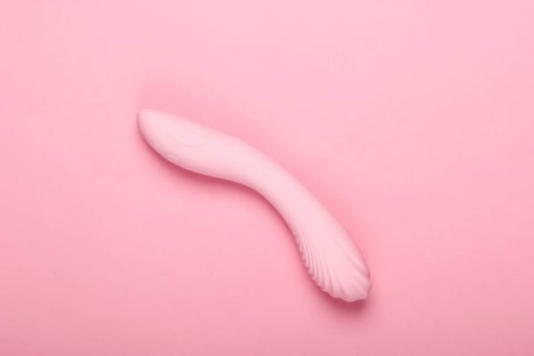 Foto colorida de um sex toy cor de rosa em um fundo da mesma cor