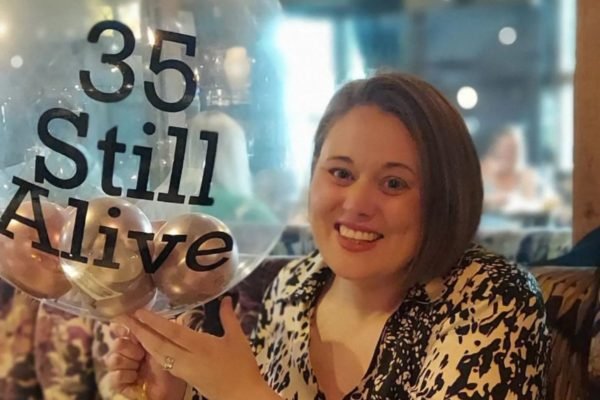 Imagem colorida de mulher segurando balão de festa de aniversário para comemorar seus 35 anos de vida - Metrópoles