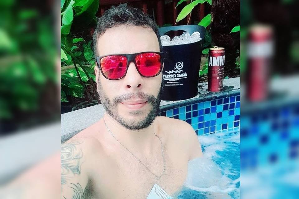 Homem de óculos escuros espelhado, vermelho, dentro da piscina. - Metrópoles