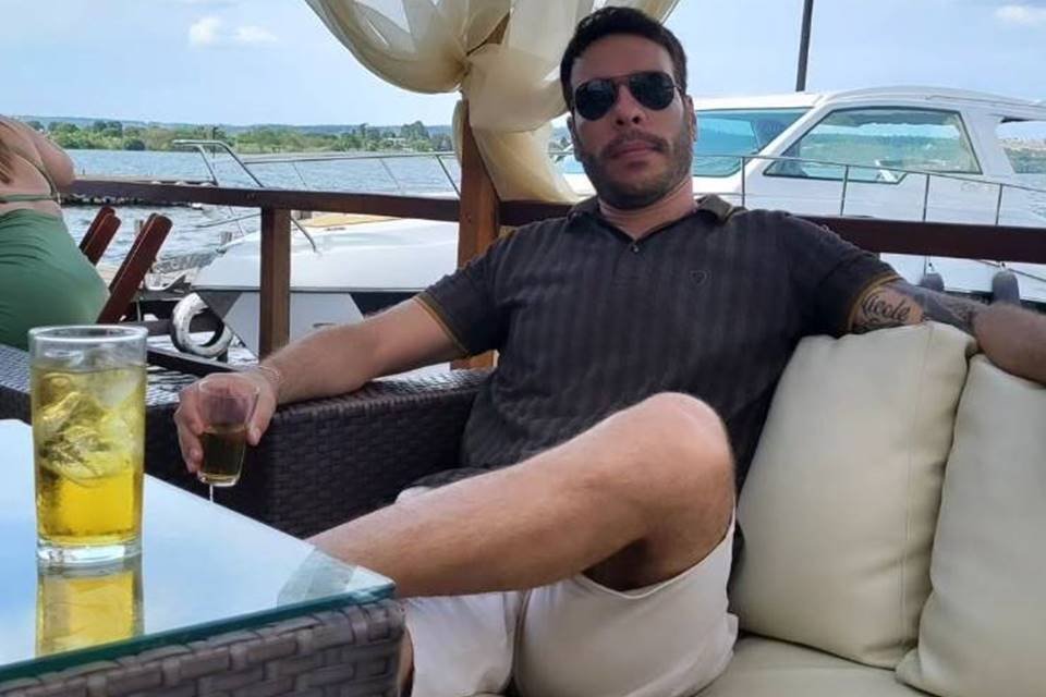Homem de óculos escuros bebe drink em lancha - Metrópoles