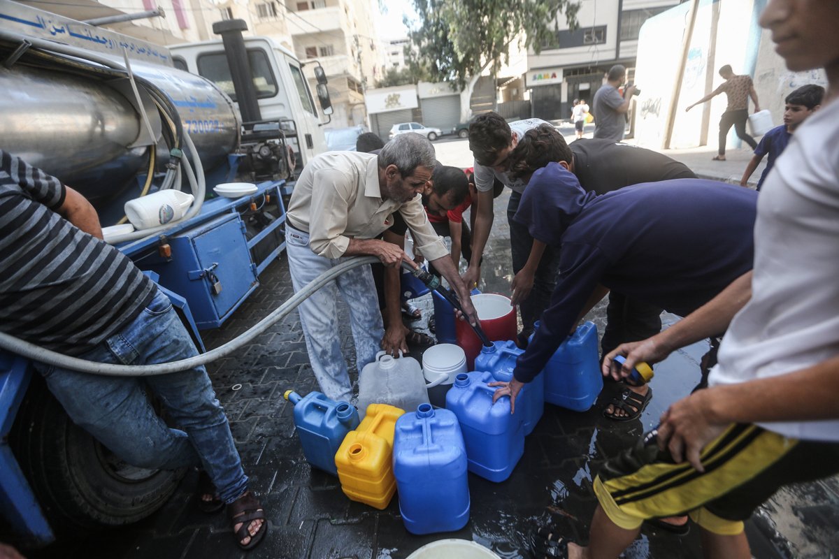 Palestinos enchem recipientes com água potável de um veículo de distribuição de água, em meio à crise hídrica causada pelo cerco israelense à Faixa de Gaza