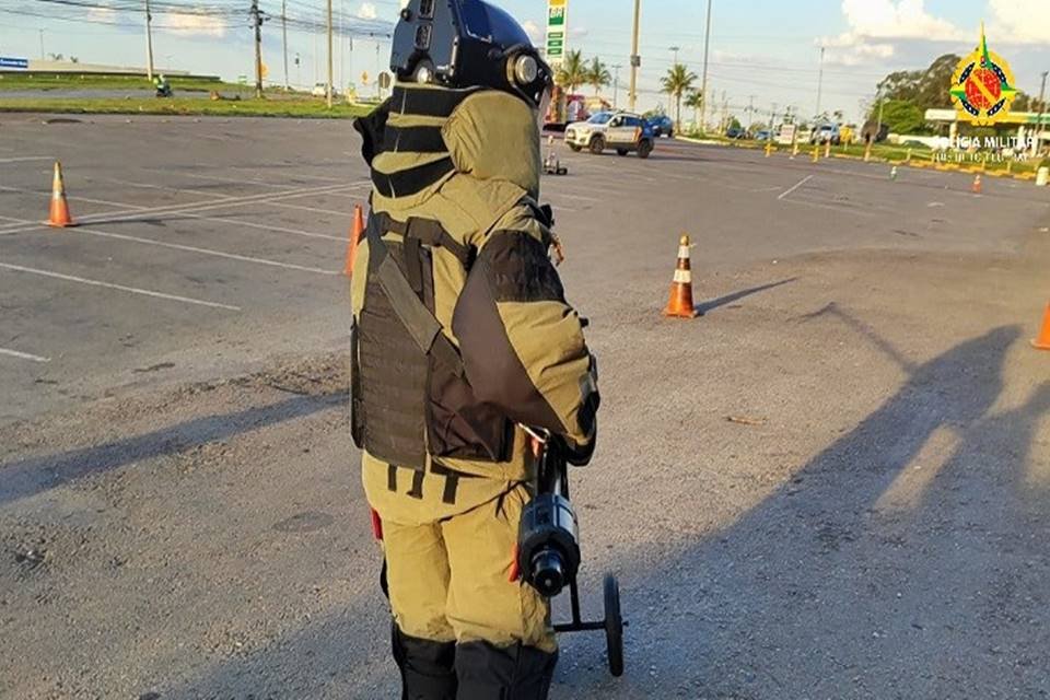 Foto colorida de policial com equipamento antibomba em meio à pista