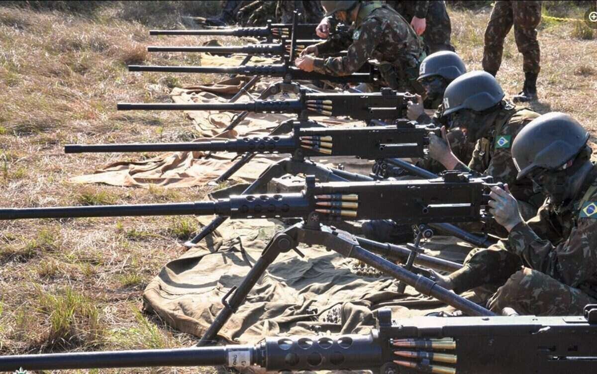 Militares com roupa camuflada lado a lado segurando metralhadoras antiaérea - Metrópoles
