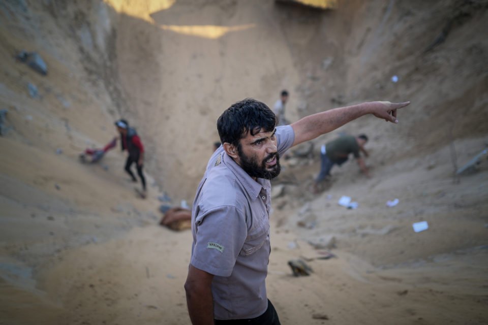 Equipes de defesa civil e moradores locais tentam resgatar pessoas dos escombros da casa destruída de uma família palestina atingida por um ataque aéreo israelense em Khan Yunis, Gaza, em 16 de outubro de 2023