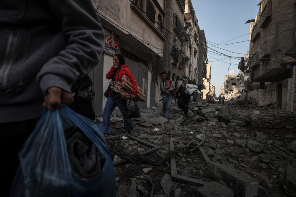 Palestinos deixam suas casas em segurança em meio aos destroços de edifícios destruídos após o ataque aéreo israelense no bairro de Tel al-Hawa enquanto os ataques israelenses continuam no 10º dia na Faixa de Gaza em 16 de outubro de 2023