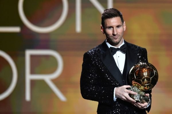 Imagem colorida de Messi segurando o prêmio da Bola de Ouro - Metrópoles