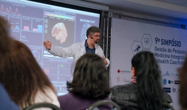 Fotografia colorida mostrando homem de jaleco apresentando caso em telão-Metrópoles