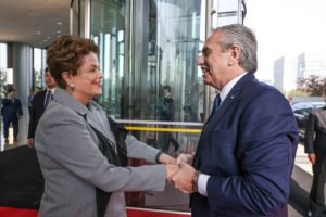 Imagem de Dilma Rousseff, presidente do Banco do Brics, e Alberto Fernández, presidente da Argentina, se cumprimentando, ambos sorridentes e apertando as mãos - Metrópoles