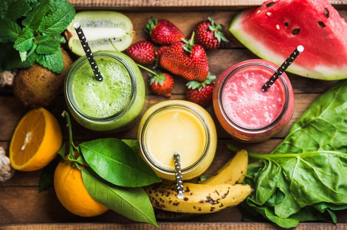 Foto colorida de três sucos ao redor de frutas - Metrópoles