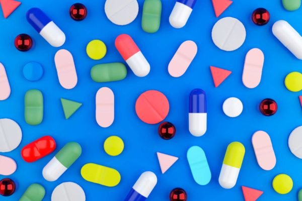 Ilustração mostra uma série de comprimidos dispostos em um fundo azul, com remédios genéricos e de marca coloridos