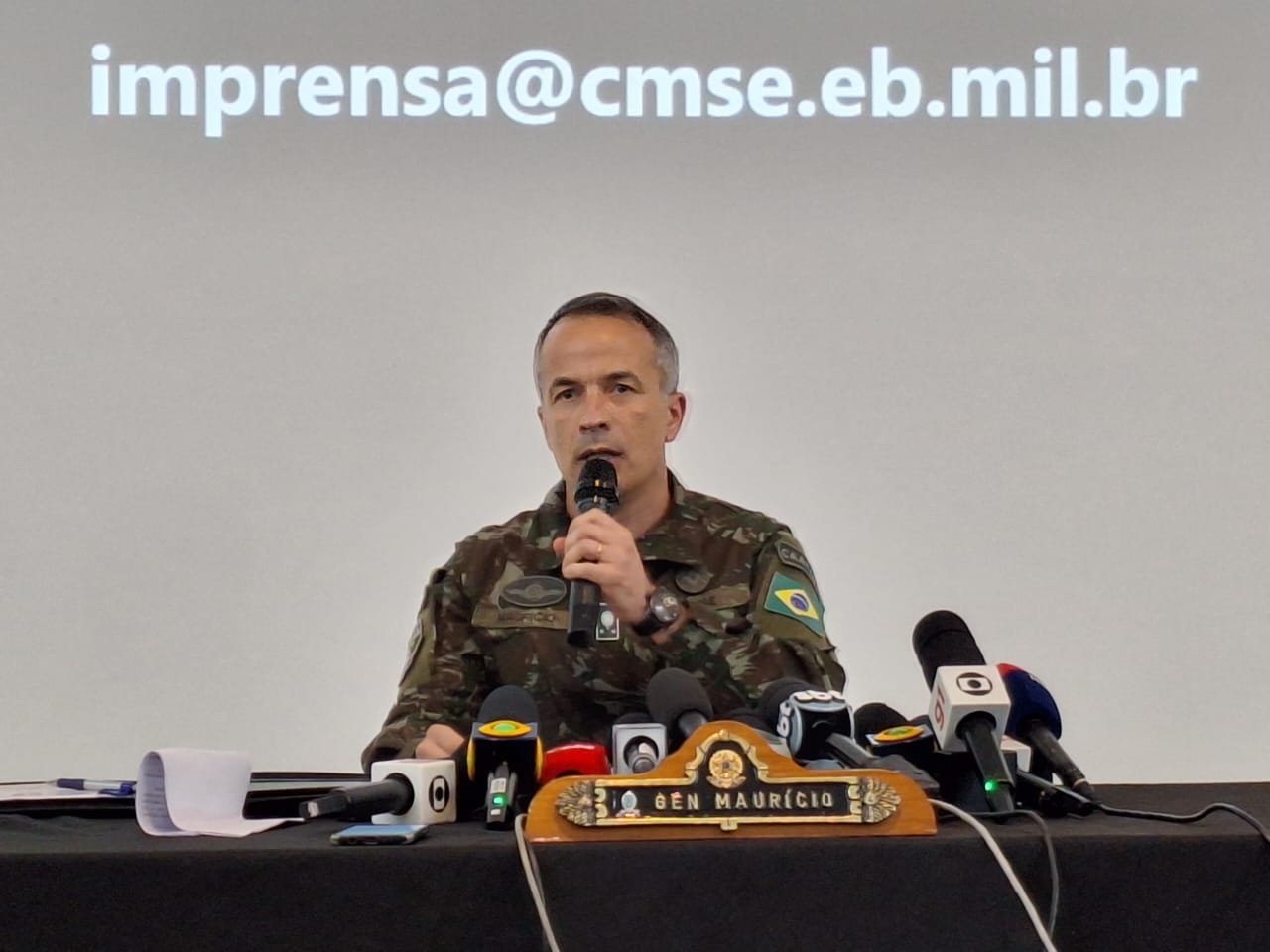 Imagem colorida mostra o General de Brigada Maurício Vieira Gama, Chefe do Estado-Maior do CMSE, um homem branco, vestido com uniforme do exército, com vários microfones à sua frente - Metrópoles