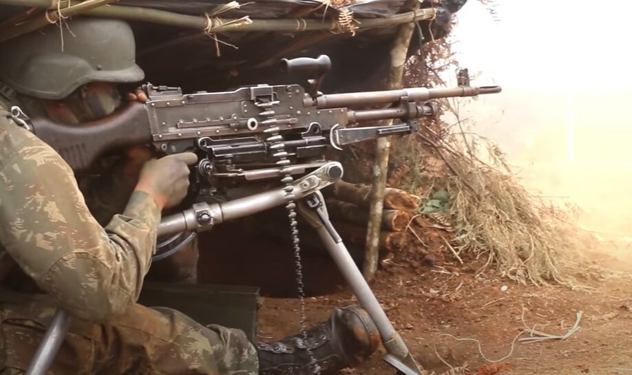 Em foto colorida militar do exército aponta com metralhadora de grosso calibre, sob proteção terrestre - Metrópoles