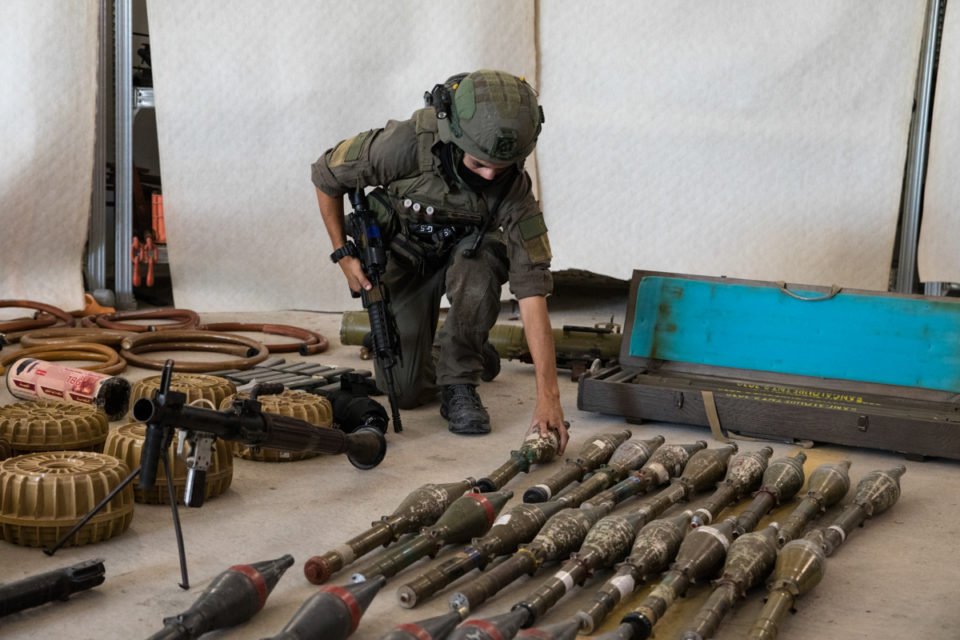 Um soldado israelense exibe equipamento militar e munições que militantes do Hamas e palestinos usaram no momento do ataque na fronteira sul de Israel com a Faixa de Gaza em 20 de outubro de 2023