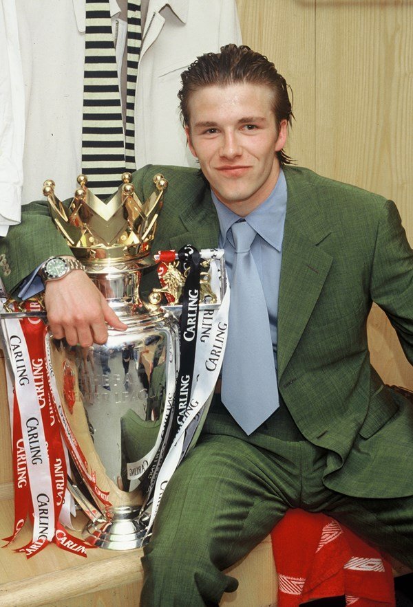 Foto em cores, David Beckham com terno segurando um troféu - Metrópoles