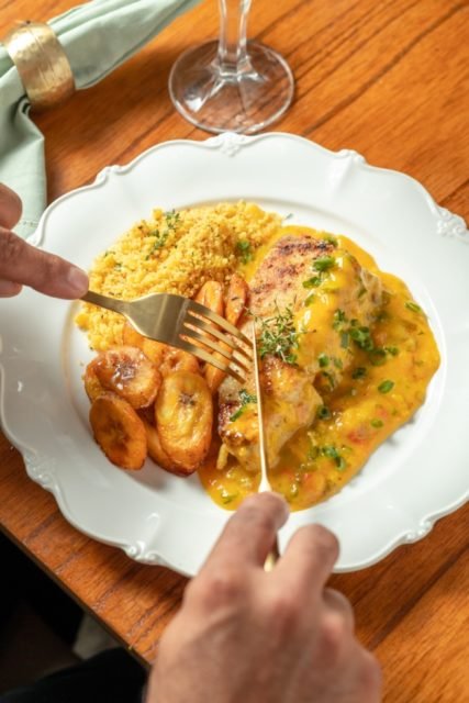 Fotografia colorida de um prato com carne branca, farofa e banana