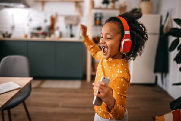 Foto mostra criança ouvindo música em um fone de ouvido colorido