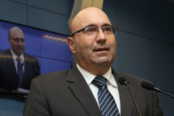 Imagem colorida mostra Dario Saad, homem branco, calvo, de óculos, vestindo terno e gravata, falando ao microfone - Metrópoles