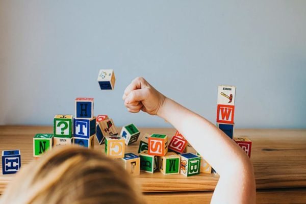Foto colorida de uma criança brincando com bloco de madeira - Metrópoles