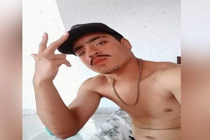 Homem branco sem camisa e boné fazendo selfie