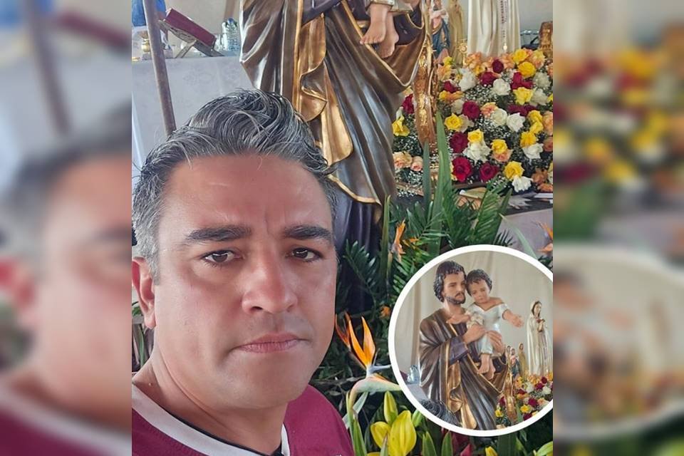 Foto colorida de homem branco com cabelo grisalho ao lado de estátuas cristãs